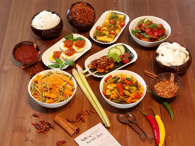 Rijsttafel Pelangi (Sambal goreng tahu – tofu met chili saus, Besengek tempe tahu – tofu met currysaus, Opor telur – gekookt ei in gele kokossaus, Sate tahu – tofu saté met pinda saus, Sayur lodeh – groenten in kokossaus, Cap cai – gebakken groenten in knoflook, Bami Goreng - gebakken noedels, Verpakking in Rumah Jawa-stijl)